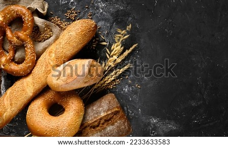 Baked bread assortment in bakery on black board background. Top view, copy space