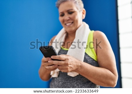 Middle age woman wearing sportswear using smartphone at sport center