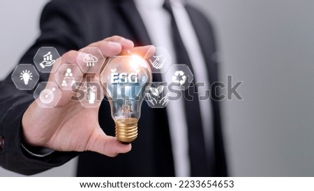 Businessman hand holding light bulb with esg icon on virtual screen, ESG Environmental, social and corporate governance concept