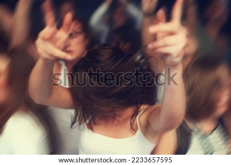 Dance, motion blur and music festival with a woman moving with rhythm in a crowd at a concert or show. Party, freedom and energy with a young female dancing at a disco or celebration event