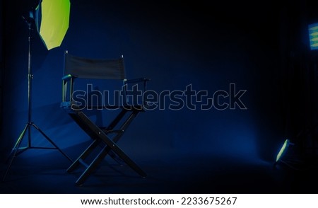 Director chair with cinema lightbox sign Director text on it and clapperboard megaphone and black background studio. Director seat on video production or filming set used in film industry. Real no 3D