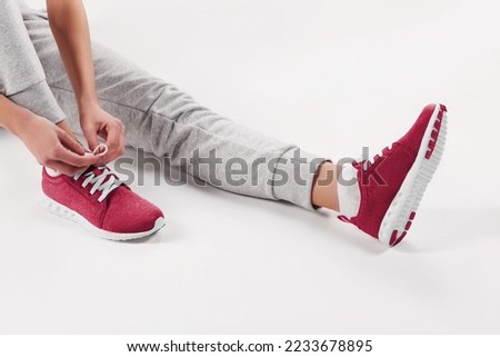 girl tying shoelaces. concept of sport and fitness. New 2023 trending PANTONE 18-1750 Viva Magenta colour
