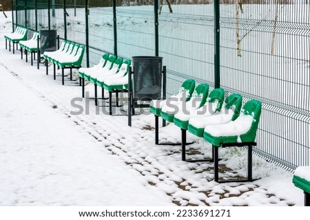 The row of empty plastic green seats at sports ground. Winter season.