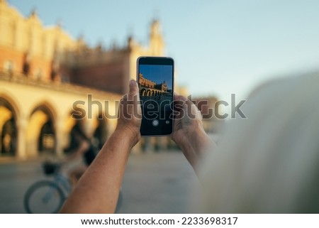 Beautiful Krakow market square, Poland, Europe. A hand taking photo of Sukiennice with smartphone, Krakow, Poland