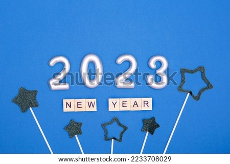 Inscription from wooden letters new year, silver numbers 2023, black stars on a blue background. The concept of celebrating the New Year. Flat lay.