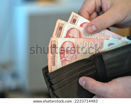 Close-up shot of 1000 Serbian dinar banknotes. A person takes money out of a wallet Royalty-Free Stock Photo #2233714483