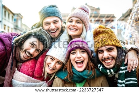 Trendy friends guys and girls taking funny selfie on warm fashion clothes - Happy life style concept with millenial people having fun together out side on winter holidays - Bright sunshine filter