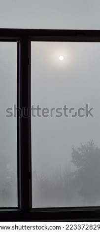 The view out the window on a heavily foggy day.Window view of moon in early morning foggy weather. Vertical photo