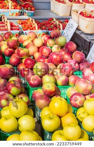 Strawberries and multi variety of apples at a farmer's market. Red and yellow apples.