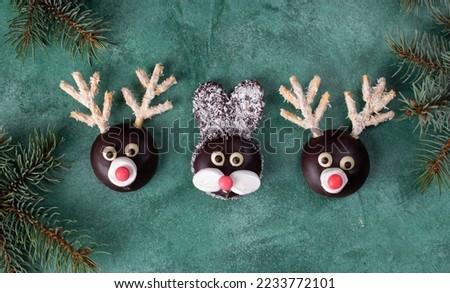 Rabbit and reindeers made of cookies, chocolate, marshmallows and coconut flakes on green background. Christmas treats for kids, Top view