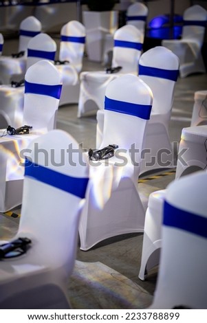 Banquet event chair with white spandex covering, blue strap, sash interpreter receiving device tight fitting Royalty-Free Stock Photo #2233788899