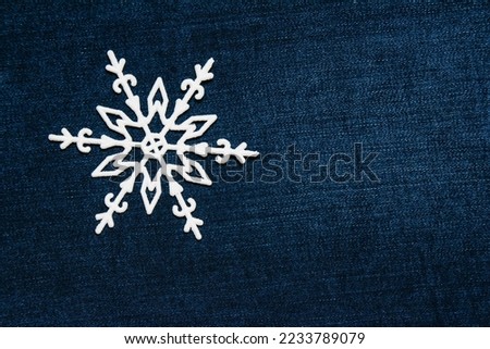 Christmas snowflake decoration on a dark denim background. Concept of preparation for the holiday.