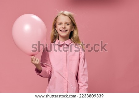 horizontal portrait of a cute beautiful, happy girl with a pink balloon in a pink dress on a pink background with an empty space for an advertising tex