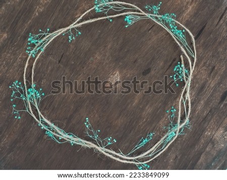 Brown rope frame and cute little blue flowers on old wooden table for vintage background.