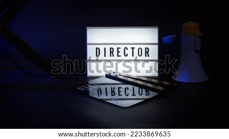 Director chair with cinema lightbox sign Director text on it and clapperboard megaphone and black background studio. Director seat on video production or filming set used in film industry. Real no 3D