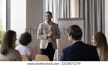 Male business trainer, professional coach gives flip chart presentation, consulting to clients or teaching employees during group training, explaining marketing strategy, provide information. Seminar Royalty-Free Stock Photo #2233871379