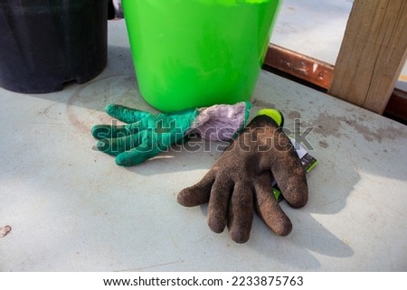 Green and brown gardening gloves on table with green bucket