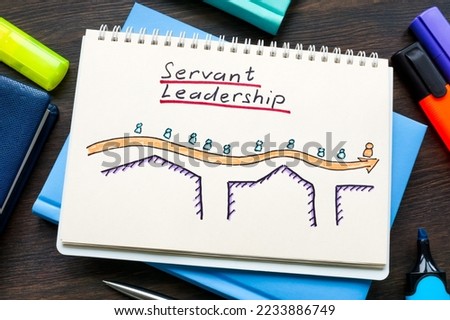 Open notepad with drawn figurines and sign Servant leadership. Royalty-Free Stock Photo #2233886749
