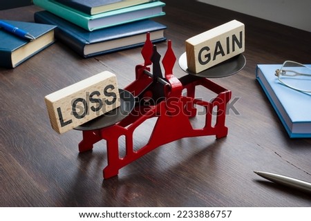 Small scales with inscriptions loss and gain on the table. Loss Aversion Bias concept. Royalty-Free Stock Photo #2233886757