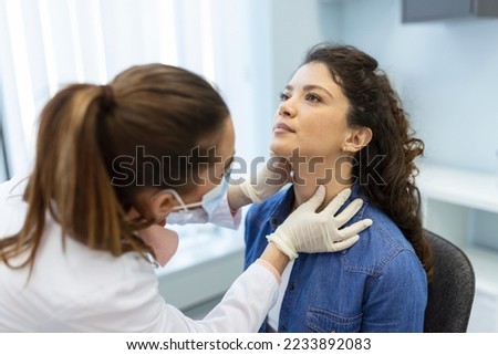 Endocrinologist examining throat of young woman in clinic. Women with thyroid gland test . Endocrinology, hormones and treatment. Inflammation of the sore throat Royalty-Free Stock Photo #2233892083