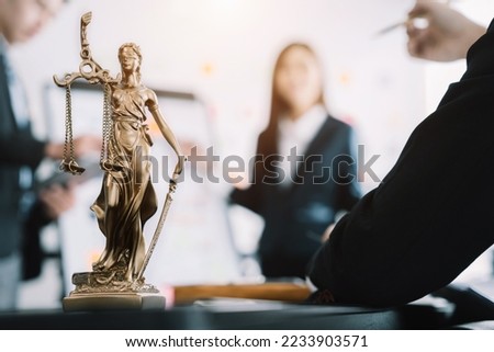 statue of justice with scales and auction hammer, the team meeting at the law firm behind the concept of in office law. Royalty-Free Stock Photo #2233903571