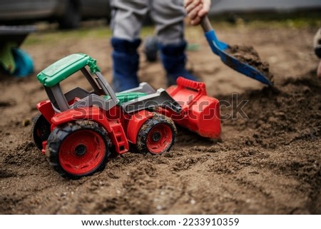 Selective ficus on excavator toy with a child digging a sand. Royalty-Free Stock Photo #2233910359