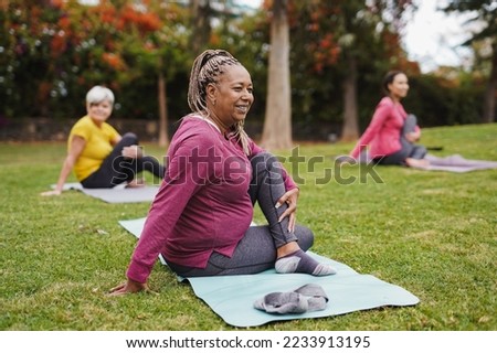Multi generational women having fun doing yoga exercise at city park together - Focus on african senior woman Royalty-Free Stock Photo #2233913195