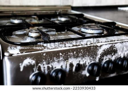 Dirty gas stove filled with detergent. Cleansing, foaming, cleaning, grease remover. Photo, macro photography