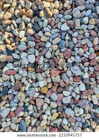 Pavement of river stones. Variation of small beach pebbles. Textured beautiful natural abstract surface for wallpapers and backgrounds. On a rainy day. Close up. Pebble texture. Stones background Royalty-Free Stock Photo #2233945757