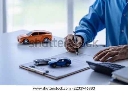 Selling a car. Management concept. The dealer gives the car keys to the new owner or renter with a contract of insurance. Customers who sign the contract and terms of the document agreement.