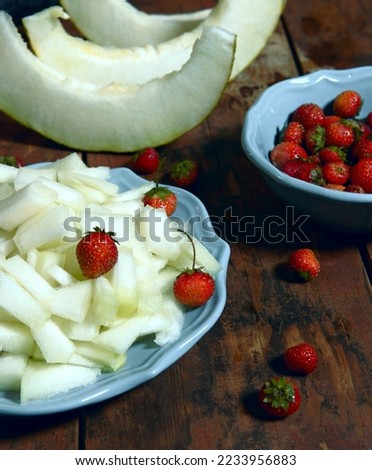 Bright atmospheric background with fruits on a dark background. Juicy melon slices and red strawberries attract the eye and awaken the appetite. A great picture for advertising banking services