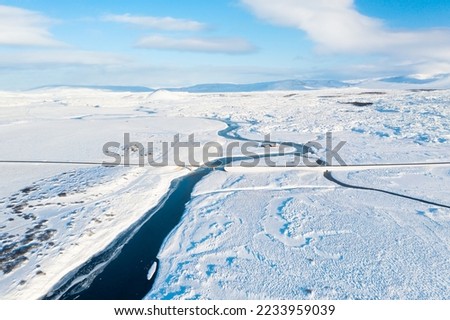 Iceland. Aerial view of the river. Road and bridge above the river. Winter landscape from a drone. Journey around the Golden Ring in Iceland. Natural winter landscape from air.