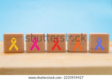 
different types of cancer symbolized in colored ribbons with wooden cube blocks. on blue background with copy space