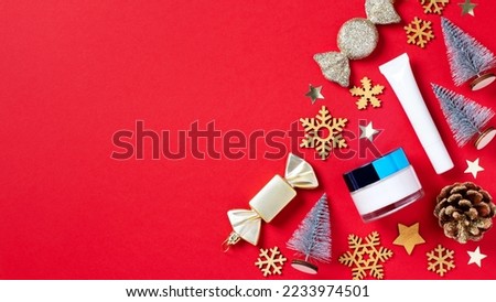 Cosmetic products and Christmas decoration and baubles on bright red background.