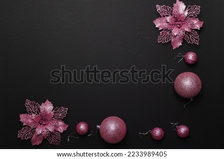 Christmas frame or border with pink flowers and pink balls on the black background with copy space