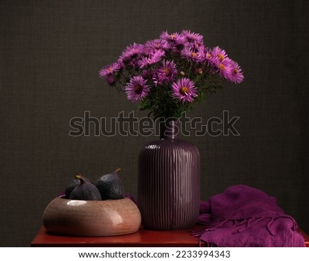 Bouquet of autumn flowers in a vase on a dark background. Lilac asters. Ripe figs. Calm still life. Autumn beauty. Postcard, congratulations. Meloncholia. The beauty of the house.