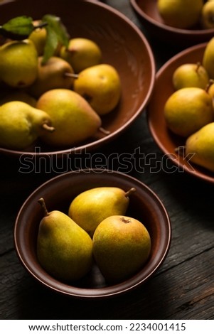 Ripe juicy pears in ceramic bowls on a dark background