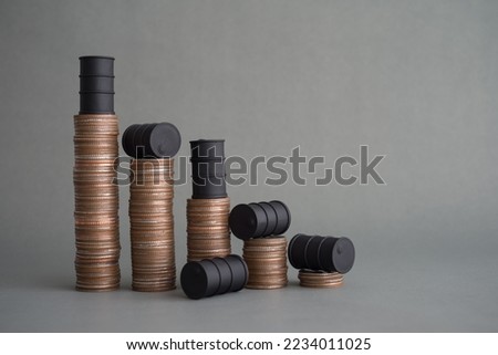Crude oil tank on stack coins as price chart graph falling down on grey background copy space. World petroleum and energy industry or trading, crude oil level of price cap, revenue reduce concept. Royalty-Free Stock Photo #2234011025