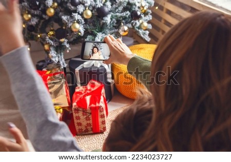 Mother with little boy son having video call with grandmother via mobile phone during holiday season, mom and kid sitting near xmas tree talking online with family via smartphone, selective focus