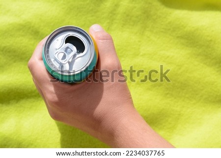 Woman holding aluminum can with beverage on yellow blanket, top view. Space for text