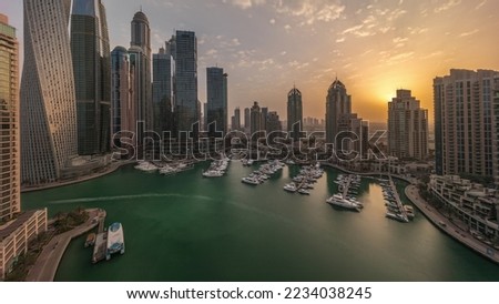 Sunrise over Dubai marina tallest skyscrapers and yachts in harbor aerial morning timelapse before sunrise. View at apartment buildings, hotels and office blocks, modern residential development of UAE