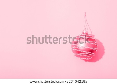 Christmas ball on pink background with sharp shadow. Top view, flat lay, copy space.