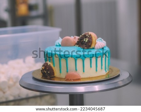 donuts meringue berries and sparkles topping on frosted icing drip turquoise cake for birthday celebration