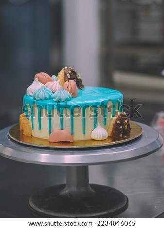 donuts meringue berries and sparkles topping on frosted icing drip turquoise cake for birthday celebration