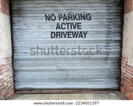 Garage door sign warning no parking in black stenciled letters