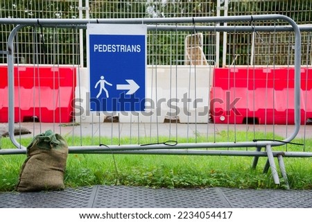 Pedestrian walkway sign at construction building site fence