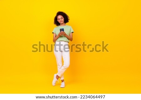 Full body size photo of young pretty nice attractive positive lady user new smartphone facebook blog isolated on bright yellow color background