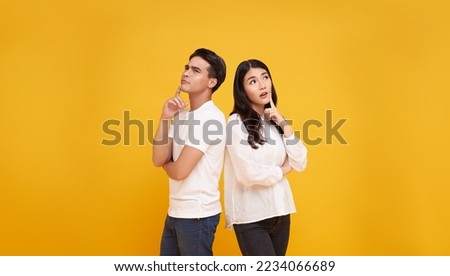 young asian man and woman thinking and touching chin while looking aside isolated on yellow background. Royalty-Free Stock Photo #2234066689
