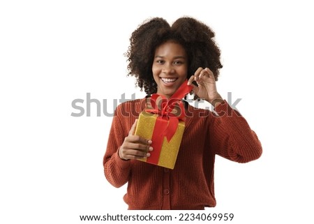 Cute african-american young woman in red knitted sweater holding gift box on white wall background. Girl smiling, she is happy to get present for Christmas festival and happy new year's.