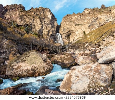 Amazing landscape view of big mountain waterfall known as Sultan, autumn grass, big stones and high rocks as a background. Caucasus nature, Jila Su Elbrus region, Kabardino-Balkaria.